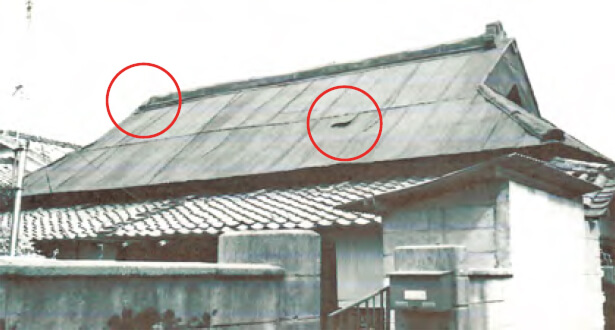 写真：左側の鬼瓦が撃ち落とされた。穴が開いた屋根はトタンで修繕