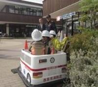 子供防火衣を着装しミニ救急車に乗車している